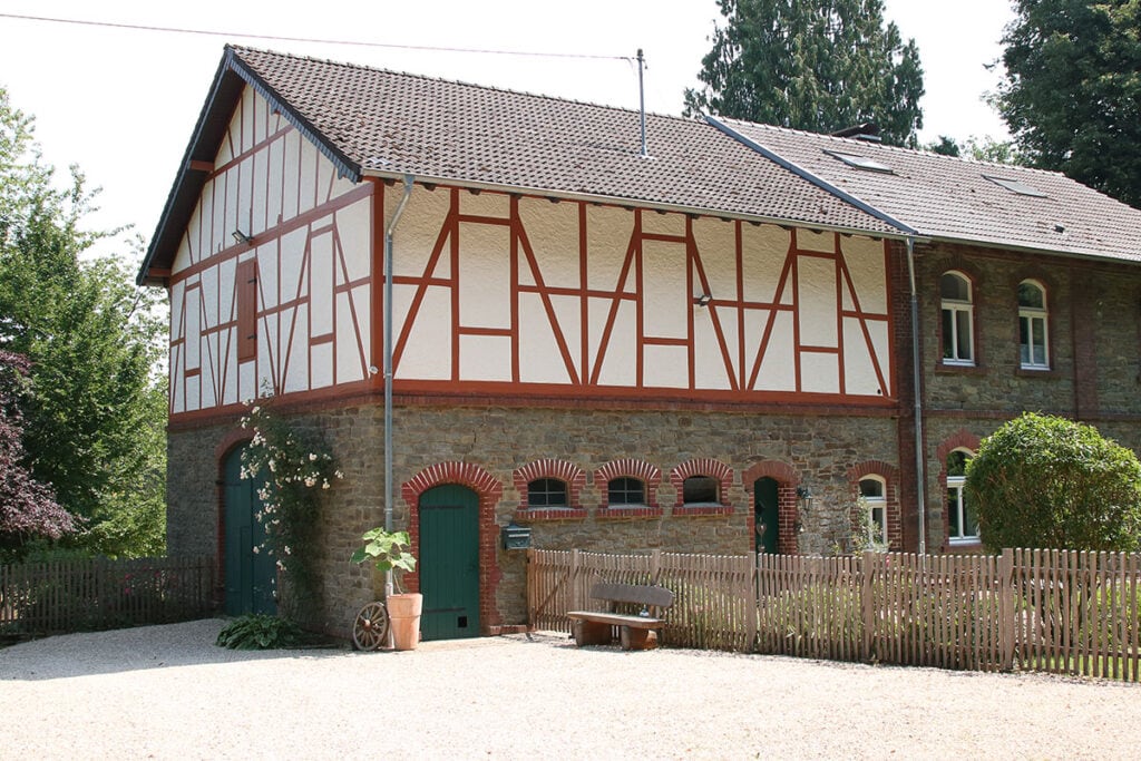 Traditionelles Fachwerkhaus mit Steinmauer und grünem Tor